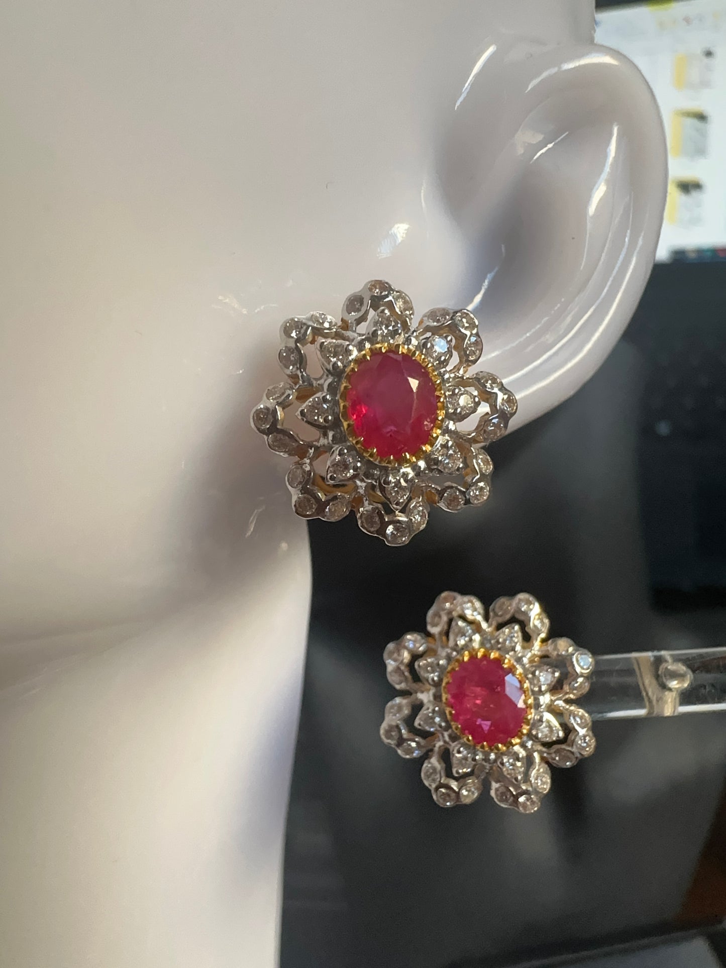 Pair of floral earrings with red center and silver details on a mannequin.