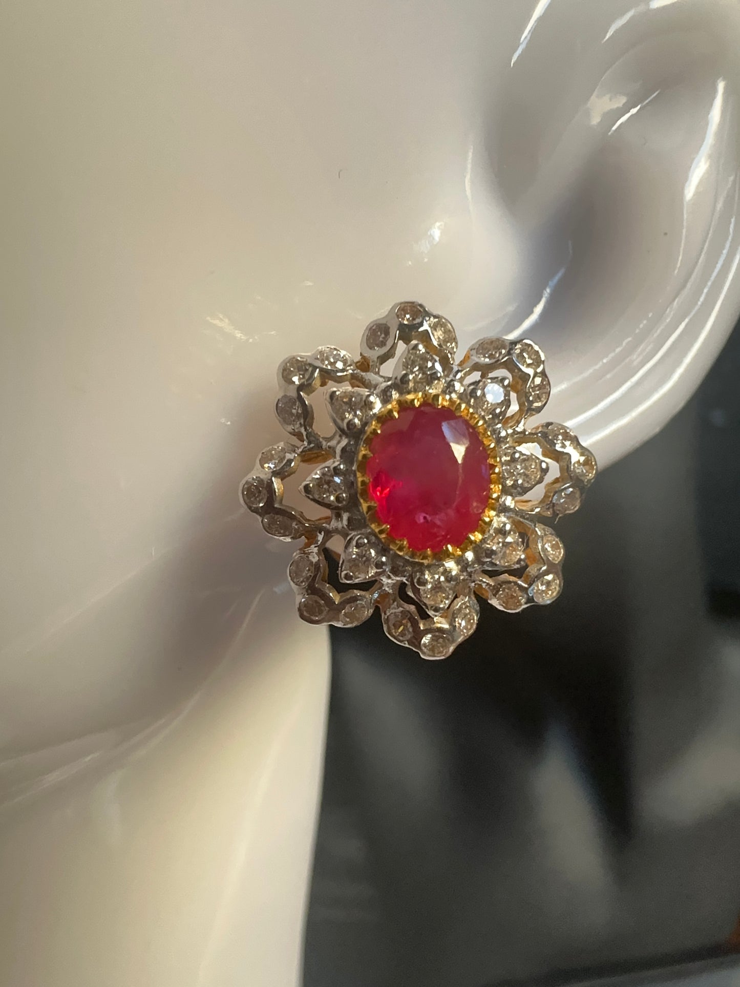 Gold ring with a red gemstone on a white surface