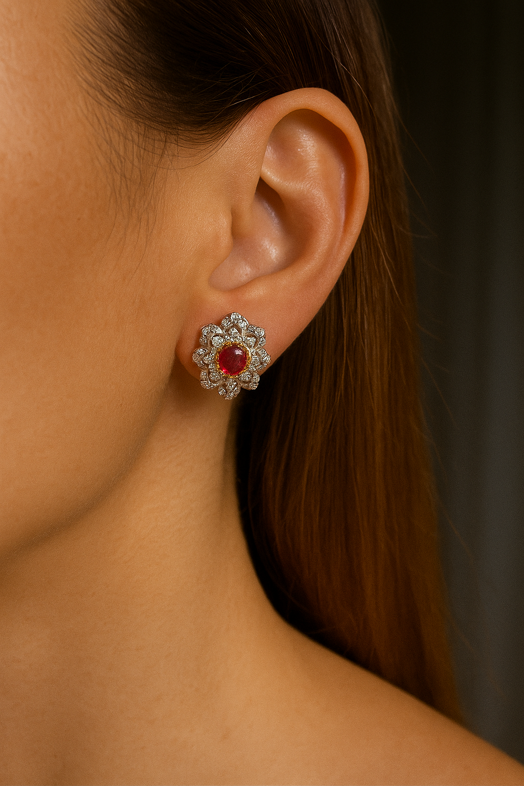 Close-up of a person wearing a sparkling earring with a red gemstone.