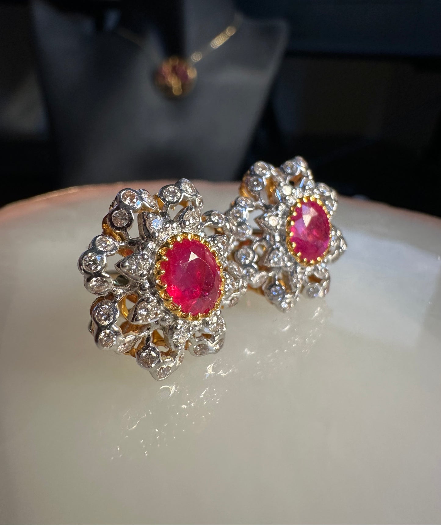 Pair of earrings with red gemstones and silver or gold accents on a white surface.